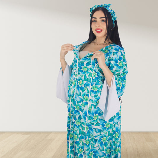 A pregnant woman wearing a blue floral maternity and nursing dress with white trim and a matching headband. The dress features a double zipper for nursing access.Maternity and breastfeeding cotton maxi dress with hijab set UAE Nursing friendly maxi dress for moms in UAE soft cotton breathable fabric.Modest maternity dress with bow and hijab for pregnancy and postpartum
